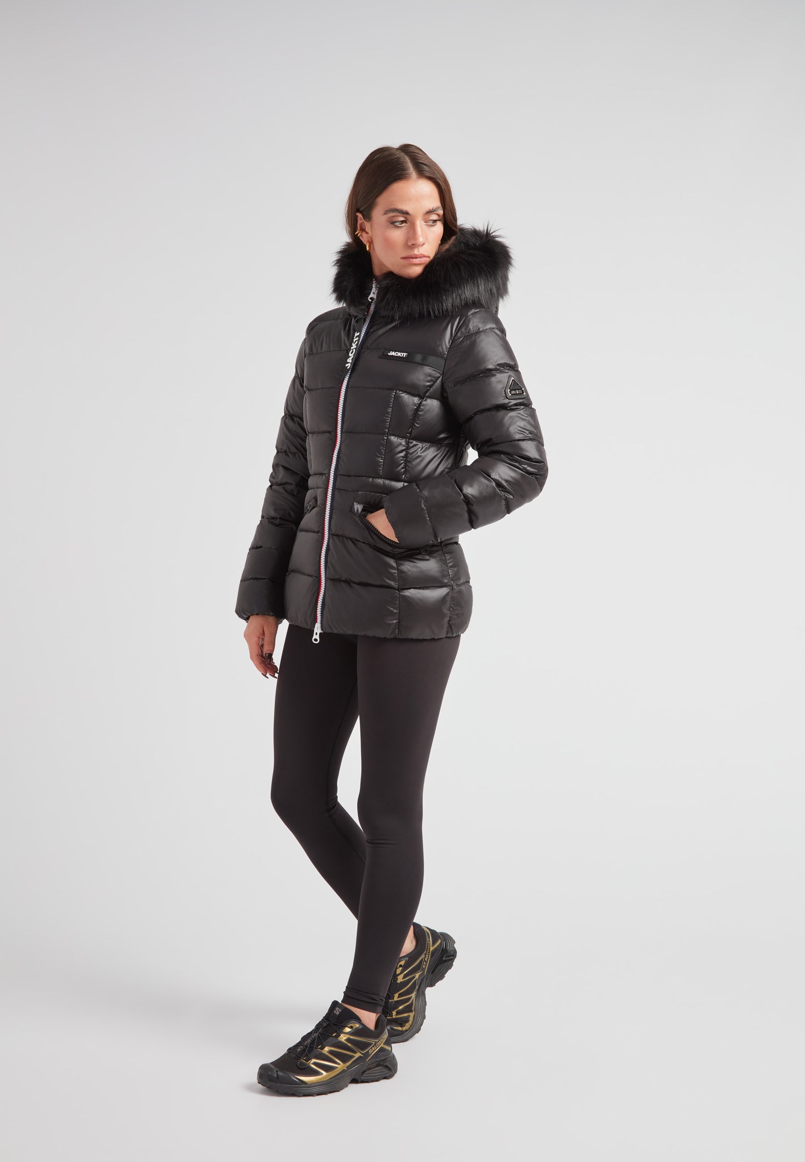 Black racer puffer jacket with fur hood worn by a model, showcasing alpine elegance and modern style.