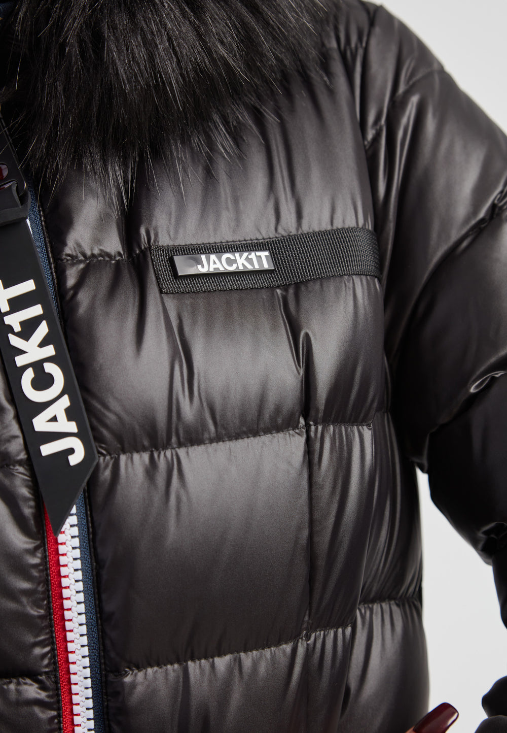 Black racer puffer jacket with fur hood featuring a sleek design and branded details.