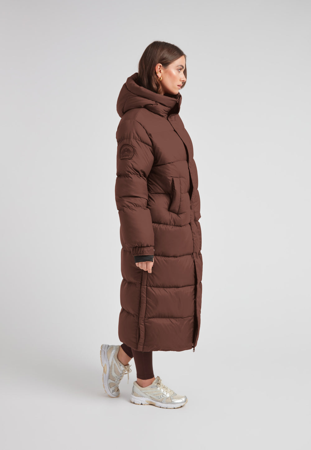 Cocoon Ultra Long Down Coat Mid Brown worn by model, showcasing its oversized silhouette and hood.