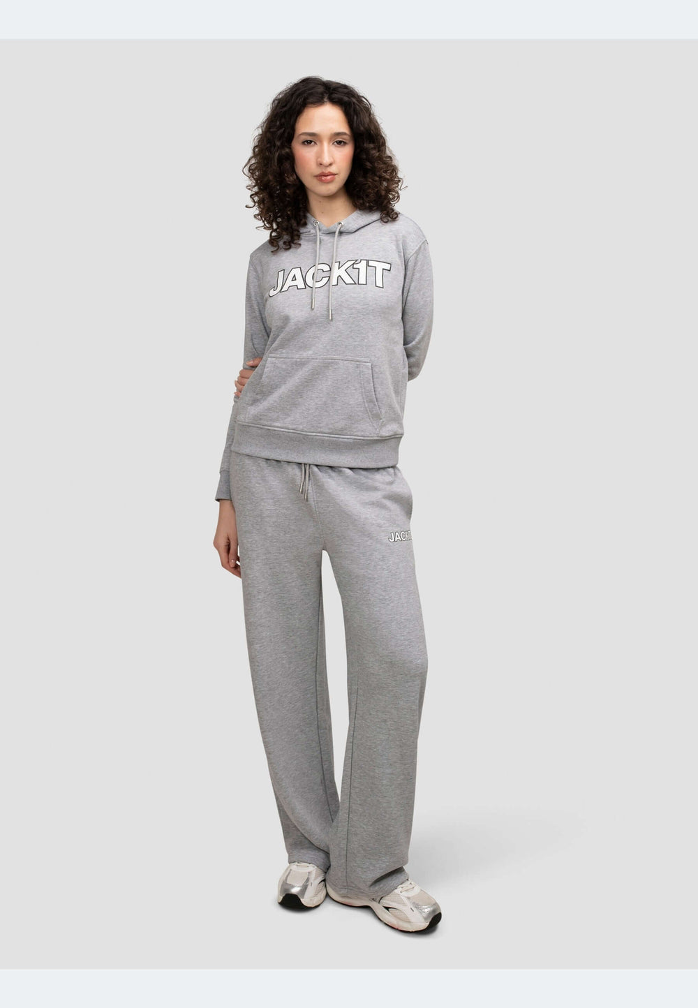 Stylish model wearing a grey hoodie with logo and matching pants in mid grey heather, showcasing relaxed comfort.