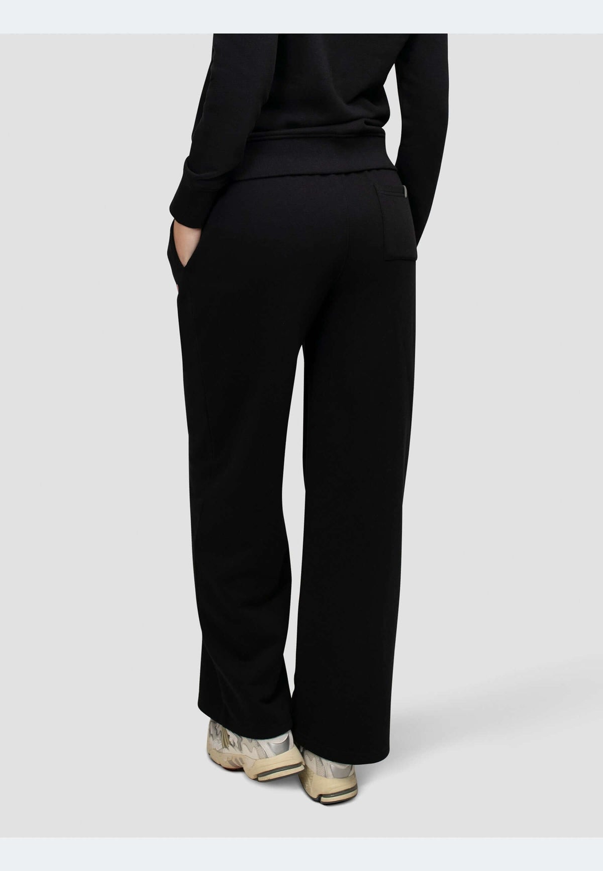 Back view of black joggers featuring relaxed wide-leg silhouette and pockets.