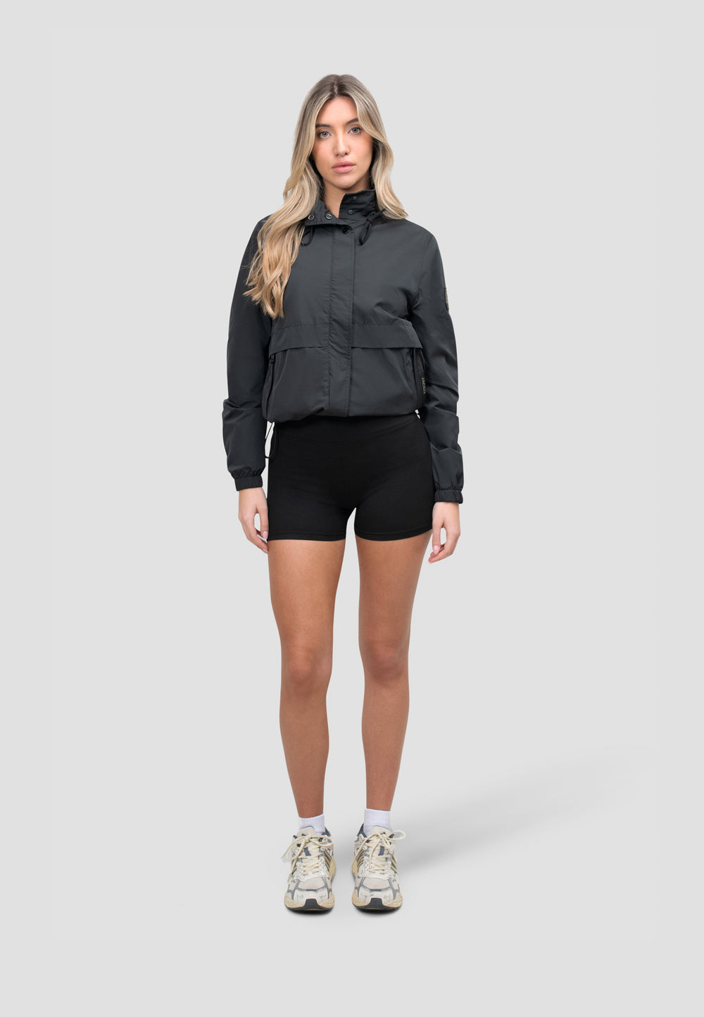 Women's Black Windbreaker worn by model, showcasing lightweight design and stow-away hood for versatile spring weather.