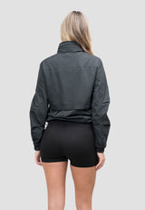 Back view of a woman wearing the Atlas Lightweight Windbreaker Black, showcasing its stylish design and fit. Womens Lightweight Windbreaker in Black.
