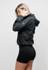 Womens Lightweight Windbreaker in Black modeled by a woman from the side, showcasing the roll out hood and elasticated cuffs.