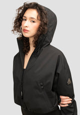 Orpheus Cropped Jacket Black worn by a model, featuring adjustable hood and zip pockets, perfect for stylish outdoor wear. Ladies Cropped Black Jacket.
