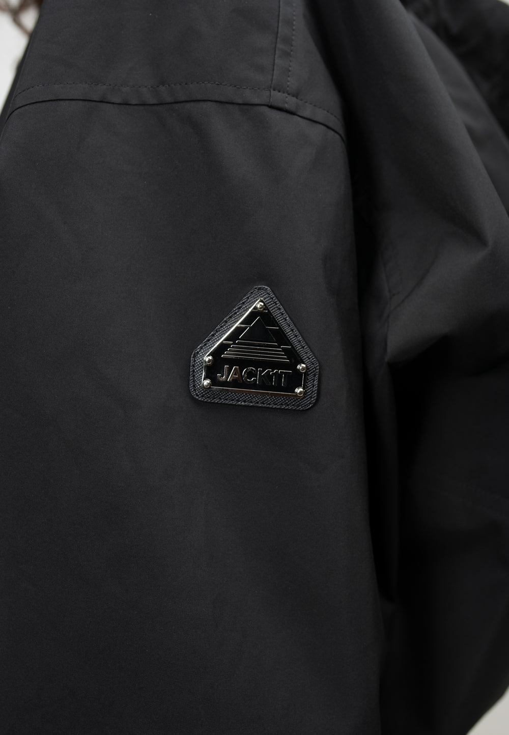 Close-up of the logo on a women's black cropped jacket, showcasing a black triangular emblem on the sleeve.