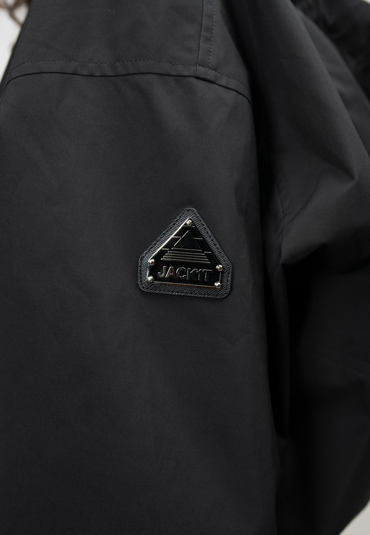 Close-up of the logo on a women's black cropped jacket, showcasing a black triangular emblem on the sleeve.