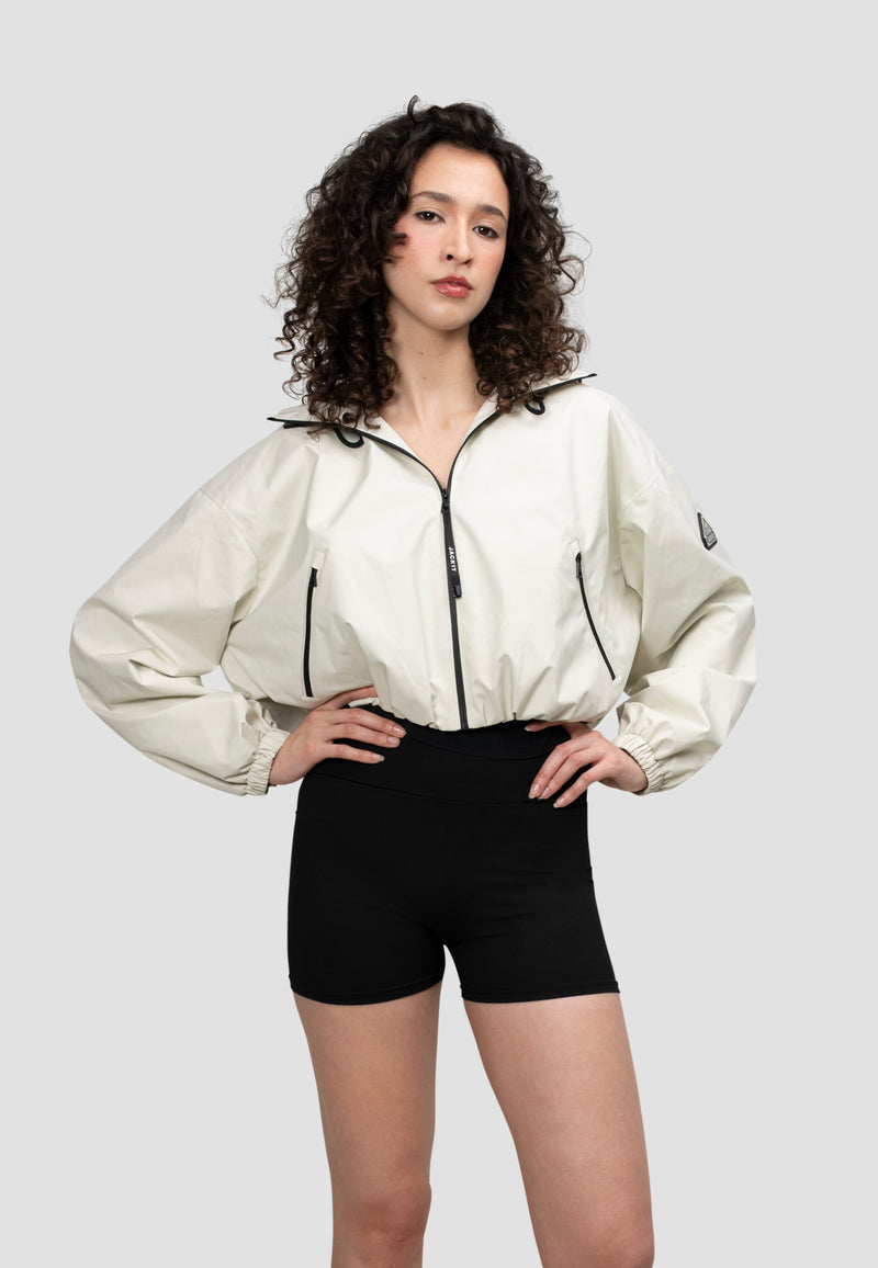 Model wearing a lightweight Ladies Cropped Cream Jacket with an elasticated waist and adjustable hood.