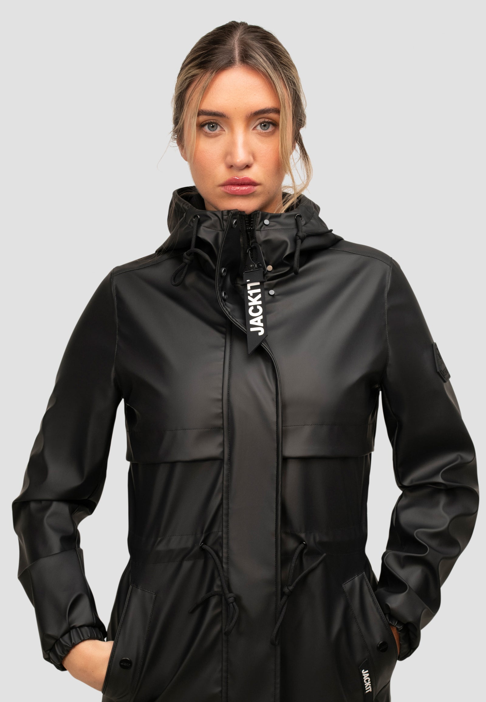Model wearing a women's black raincoat with a hood, showcasing a sleek design and water-resistant features.