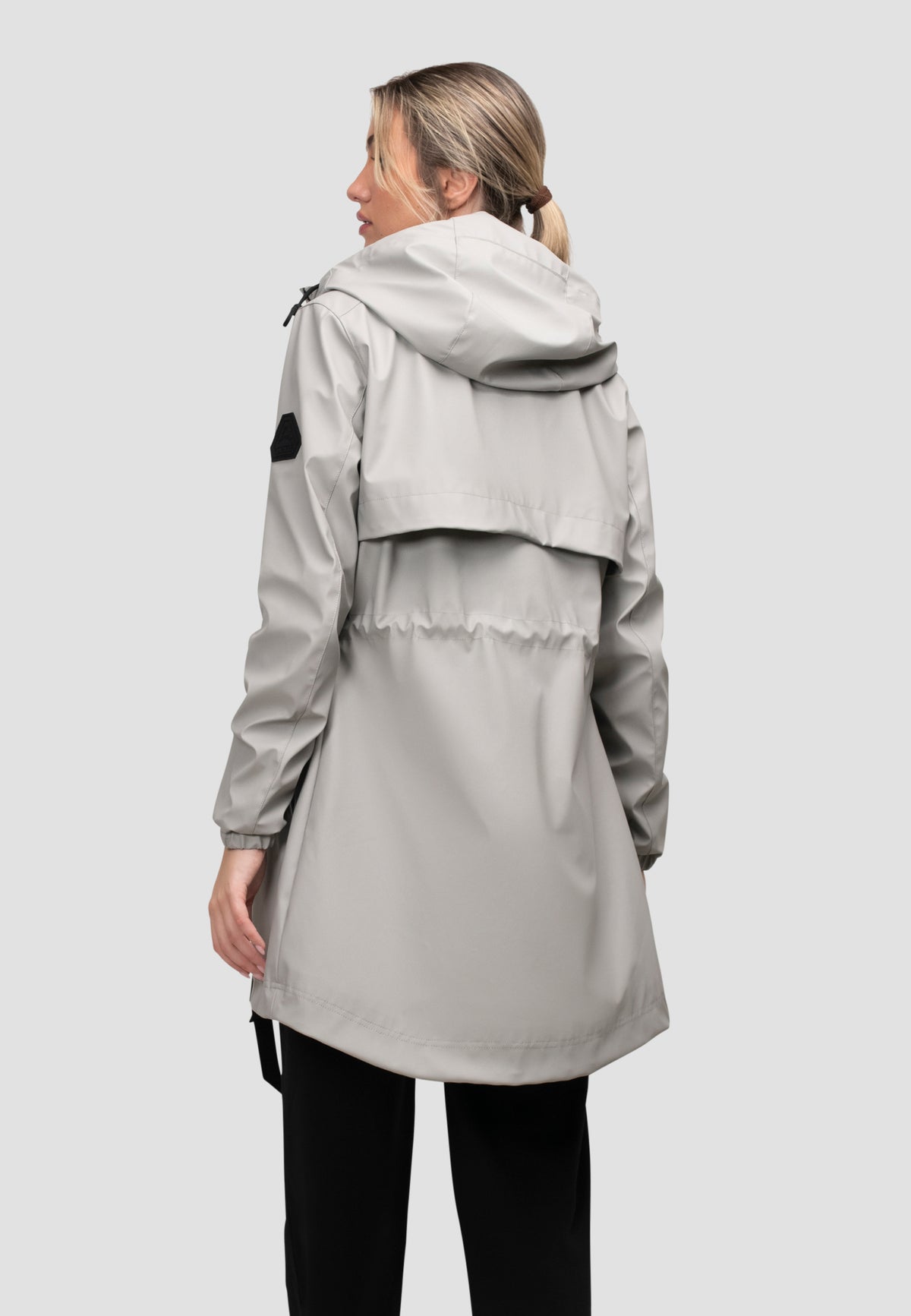Back view of a lightweight women's grey raincoat with cape design in dusty light grey, perfect for unpredictable weather.