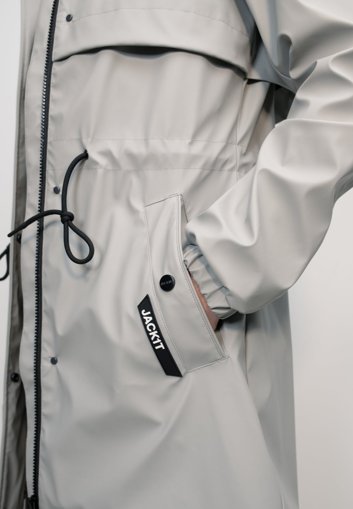 Close-up of women's grey raincoat with cape showing pocket detail, perfect for unpredictable weather.