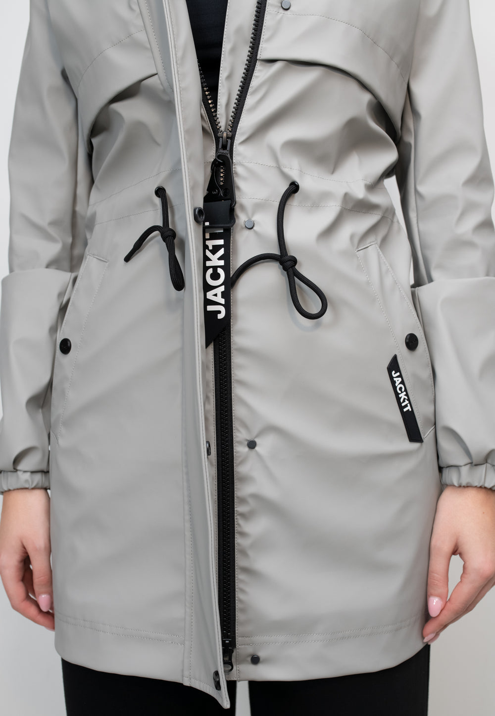 Close-up of women's grey raincoat featuring adjustable drawstrings and zipper detail.