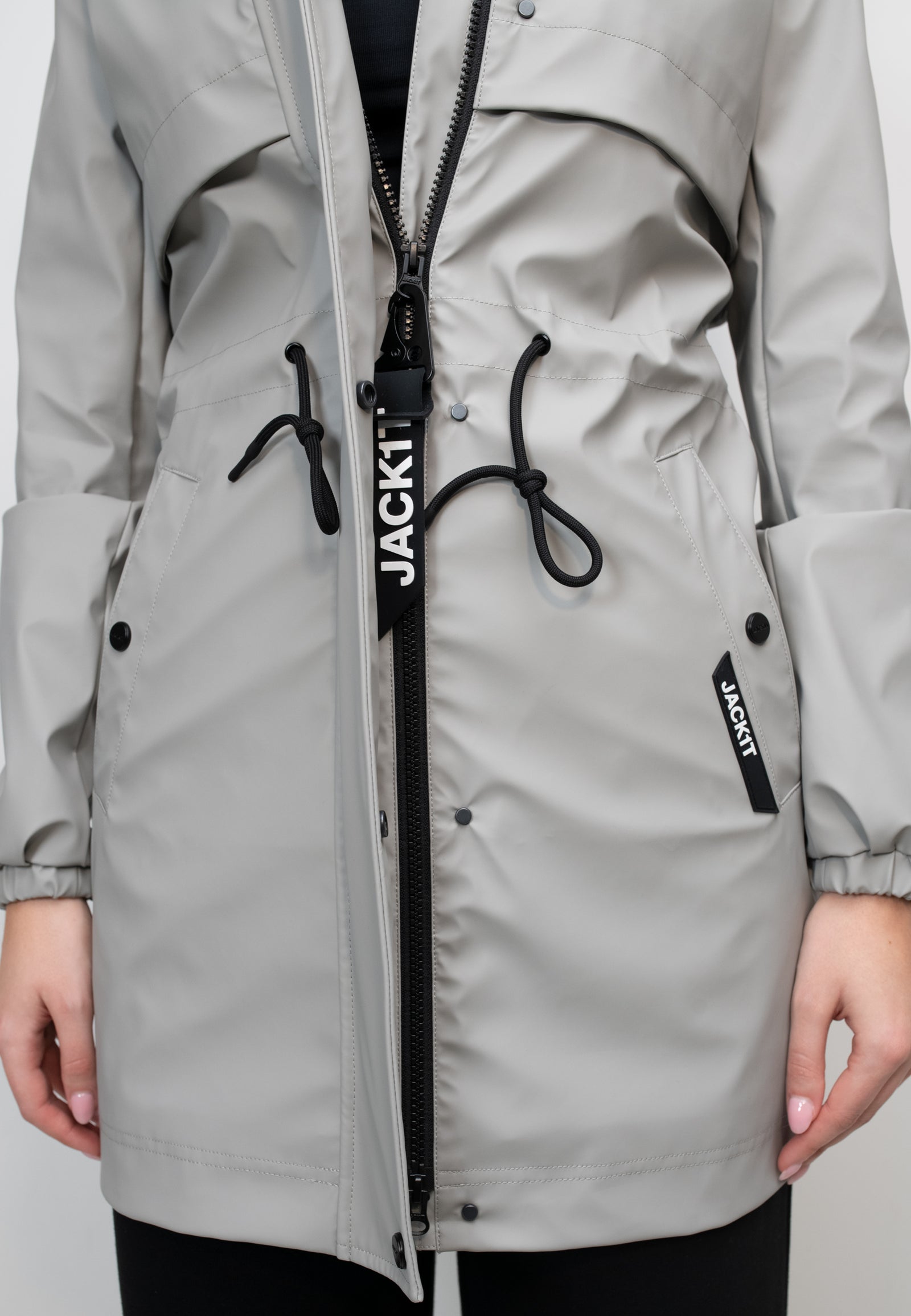 Close-up of women's grey raincoat featuring adjustable drawstrings and zipper detail.