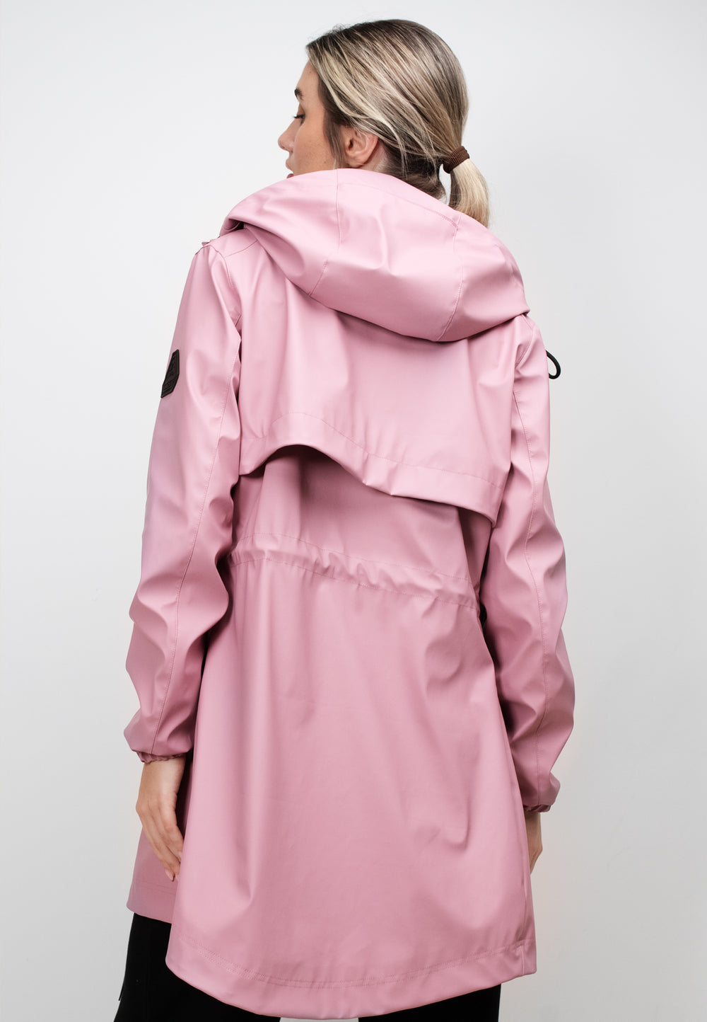 Back view of a woman wearing a lightweight women's pink raincoat with cape in dusty pink.