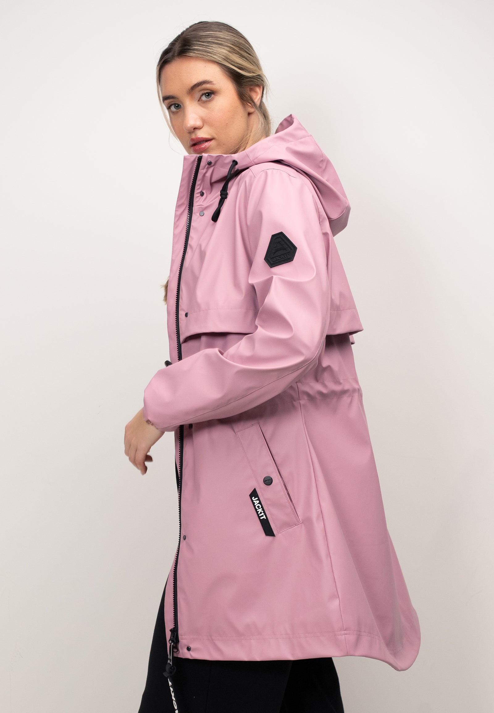 Model wearing a women's pink raincoat with cape in dusty pink, showcasing a lightweight and stylish design.