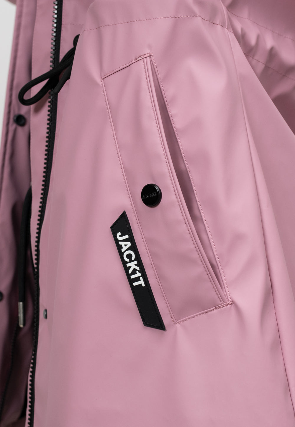 Close-up of women's pink raincoat showing pocket detail and logo, lightweight and stylish design for spring weather.