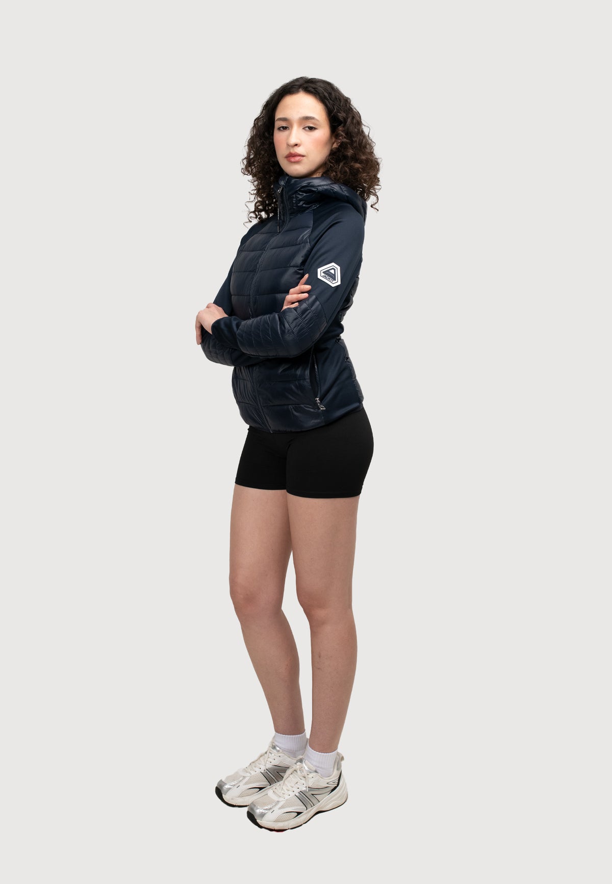 Model in a women's navy hooded jacket, showcasing lightweight fabric and sporty style.