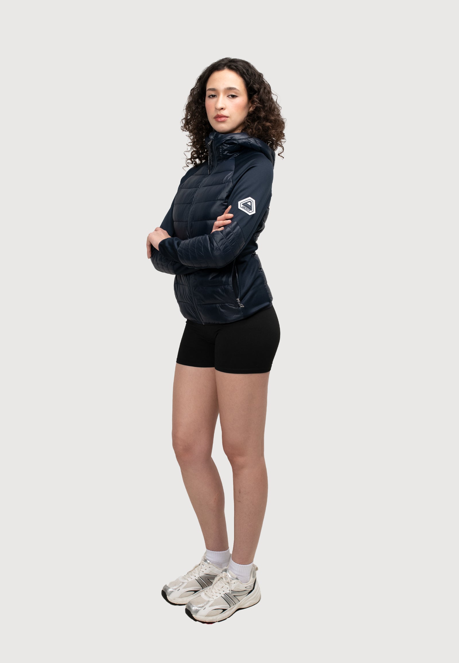 Model in a women's navy hooded jacket, showcasing lightweight fabric and sporty style.