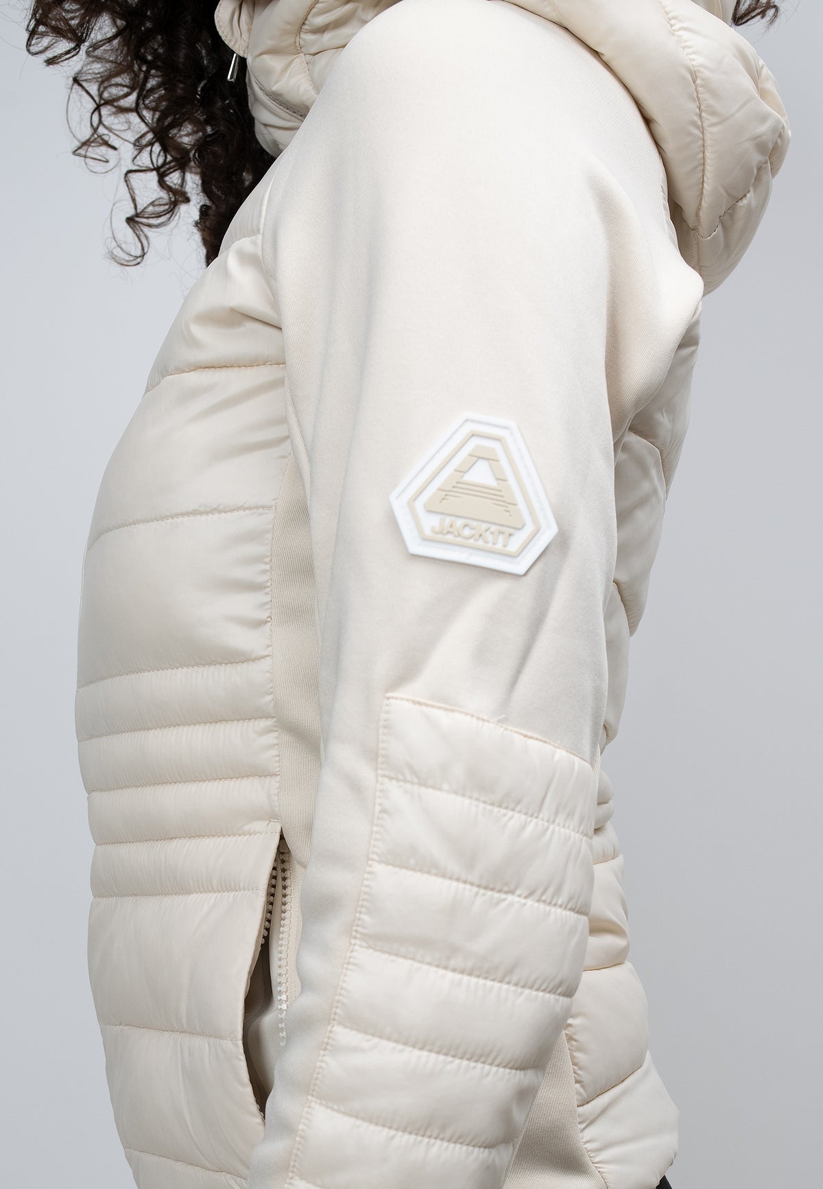 Close-up of a woman's cream hooded jacket showcasing the side view and logo detail.