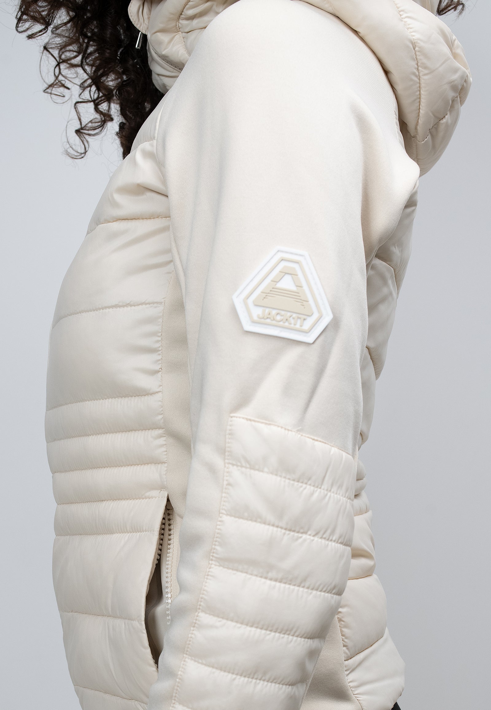 Close-up of a woman's cream hooded jacket showcasing the side view and logo detail.