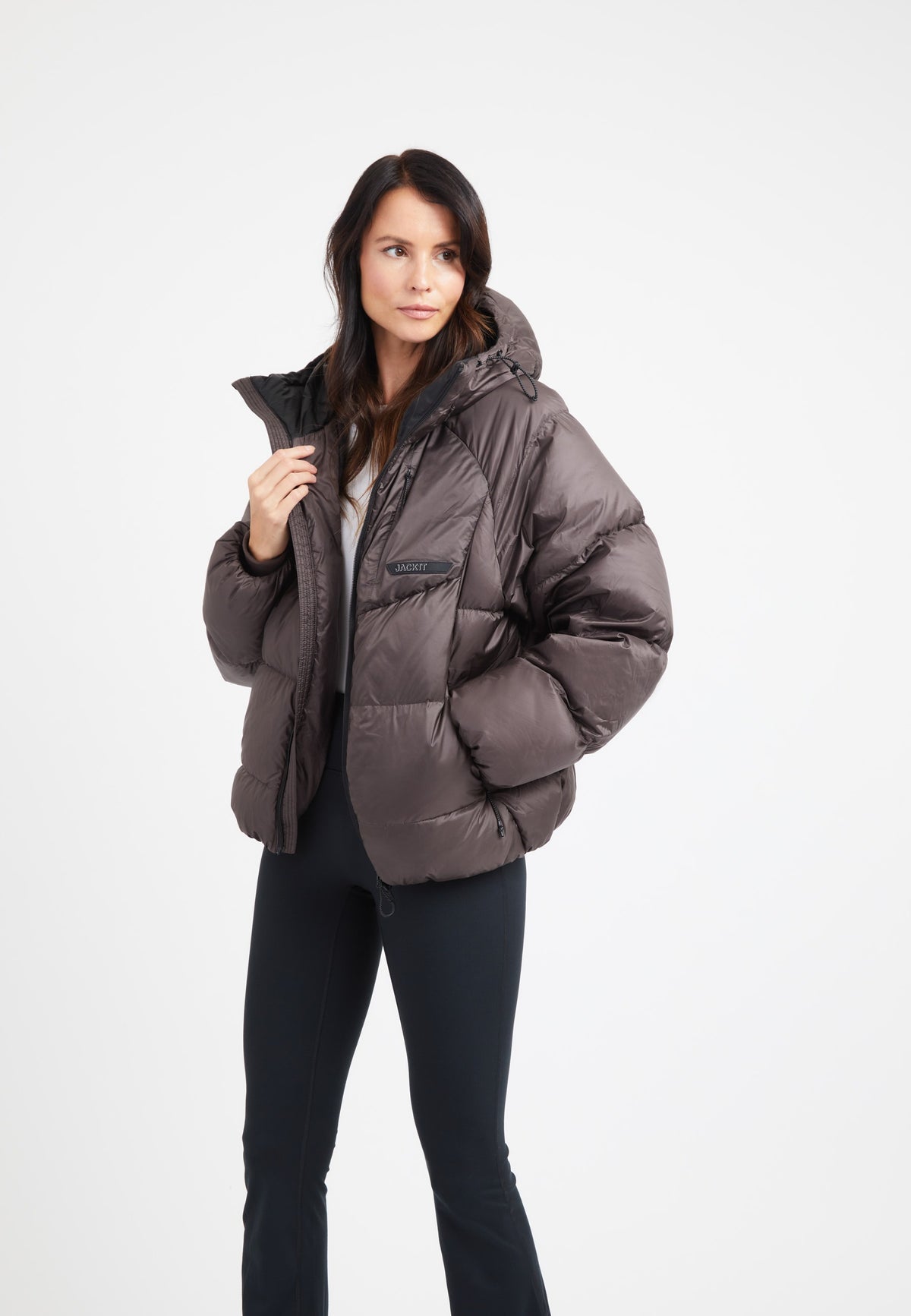 Model wearing an oversized puffer brown jacket with an adjustable hood in a modern silhouette.
