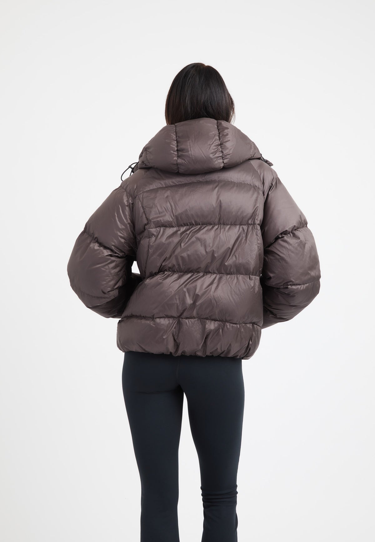 Back view of oversized puffer brown jacket with adjustable hood and puffy silhouette.