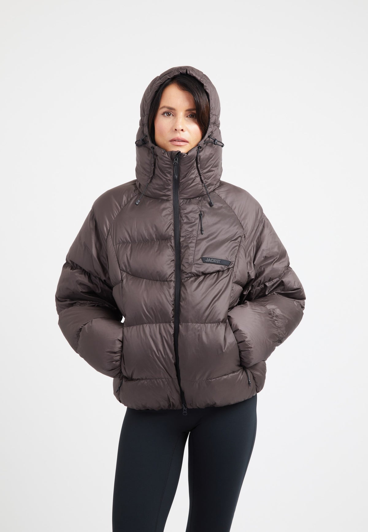 Model wearing an oversized puffer brown jacket with a hood, showcasing a modern design and RDS certified down fill.