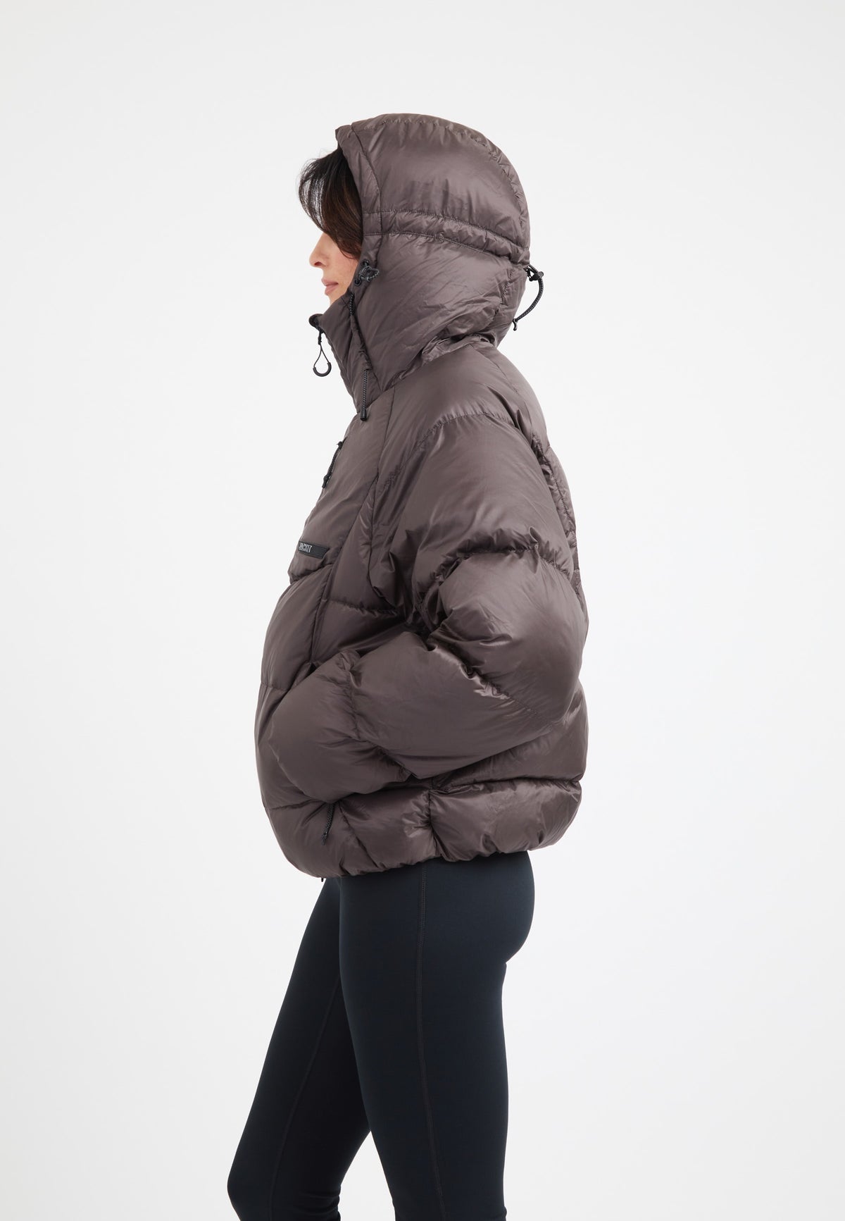 Side view of an oversized puffer brown jacket with an adjustable hood and dark fabric, ideal for winter wear.