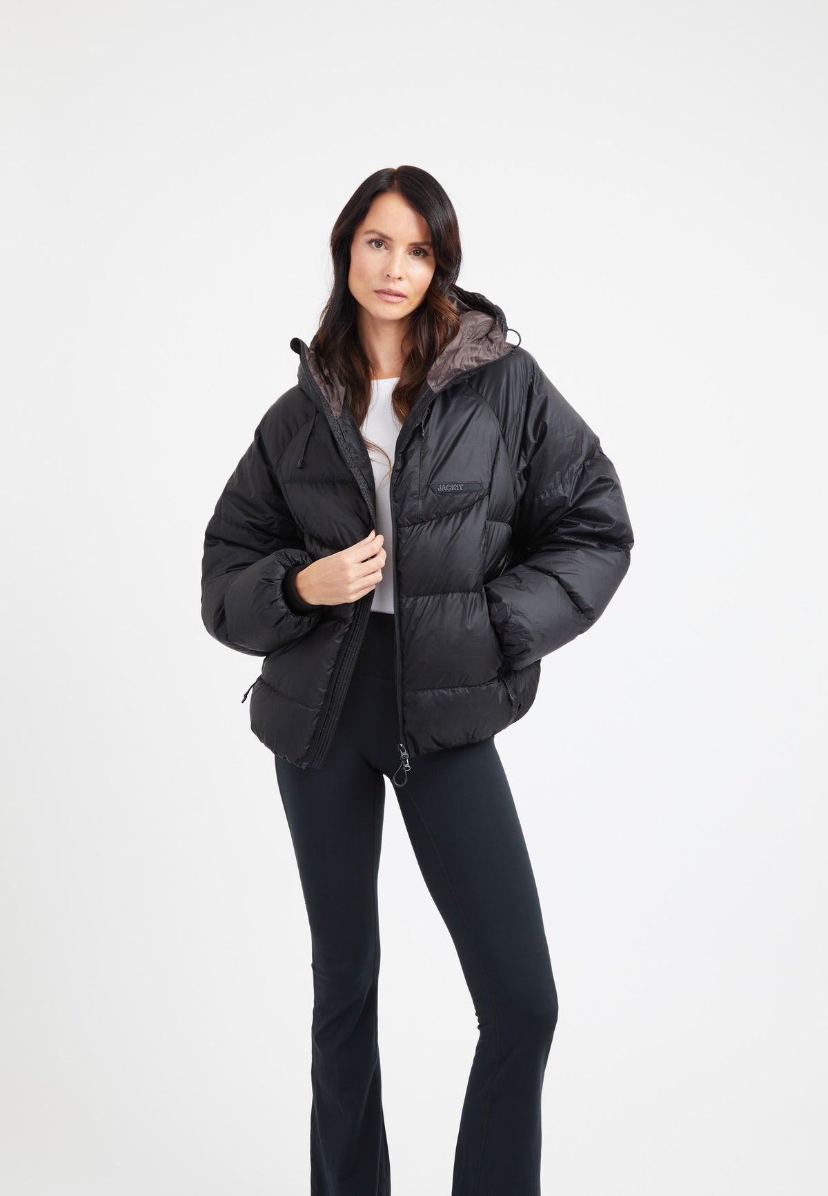 Model wearing an oversized puffer black jacket with adjustable hood and fleece lined pockets.