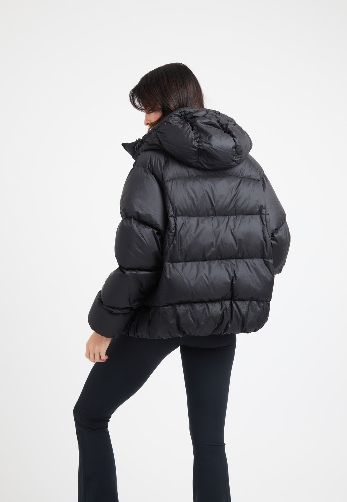 Woman wearing an oversized puffer black jacket with a hood, stylish and modern design.
