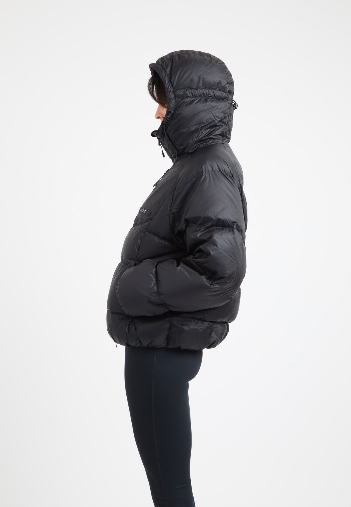 Model wearing an oversized puffer black jacket with an adjustable hood and fleece lined pockets.