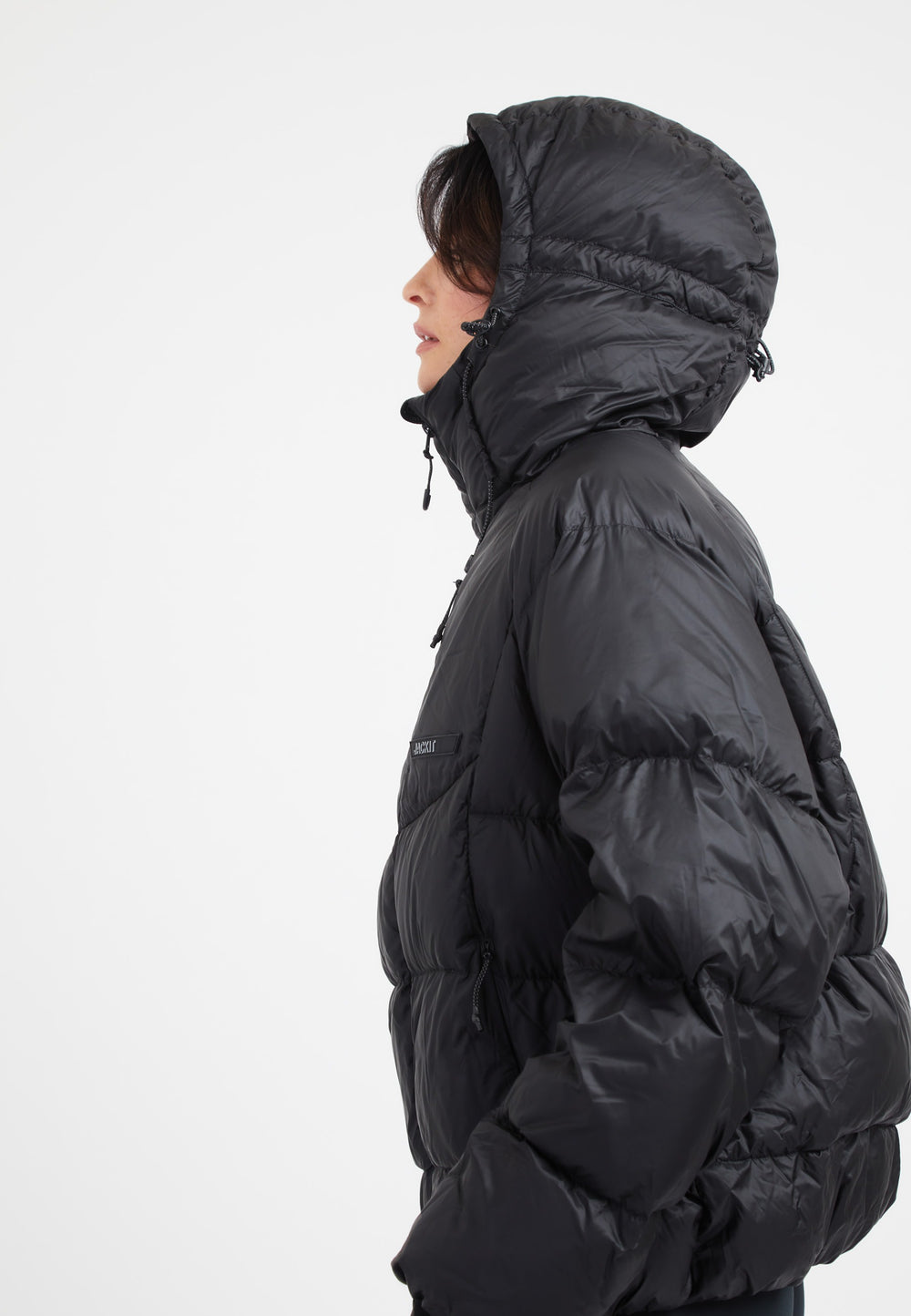 Modern oversized puffer black jacket with adjustable hood and fabric storm cuffs.
