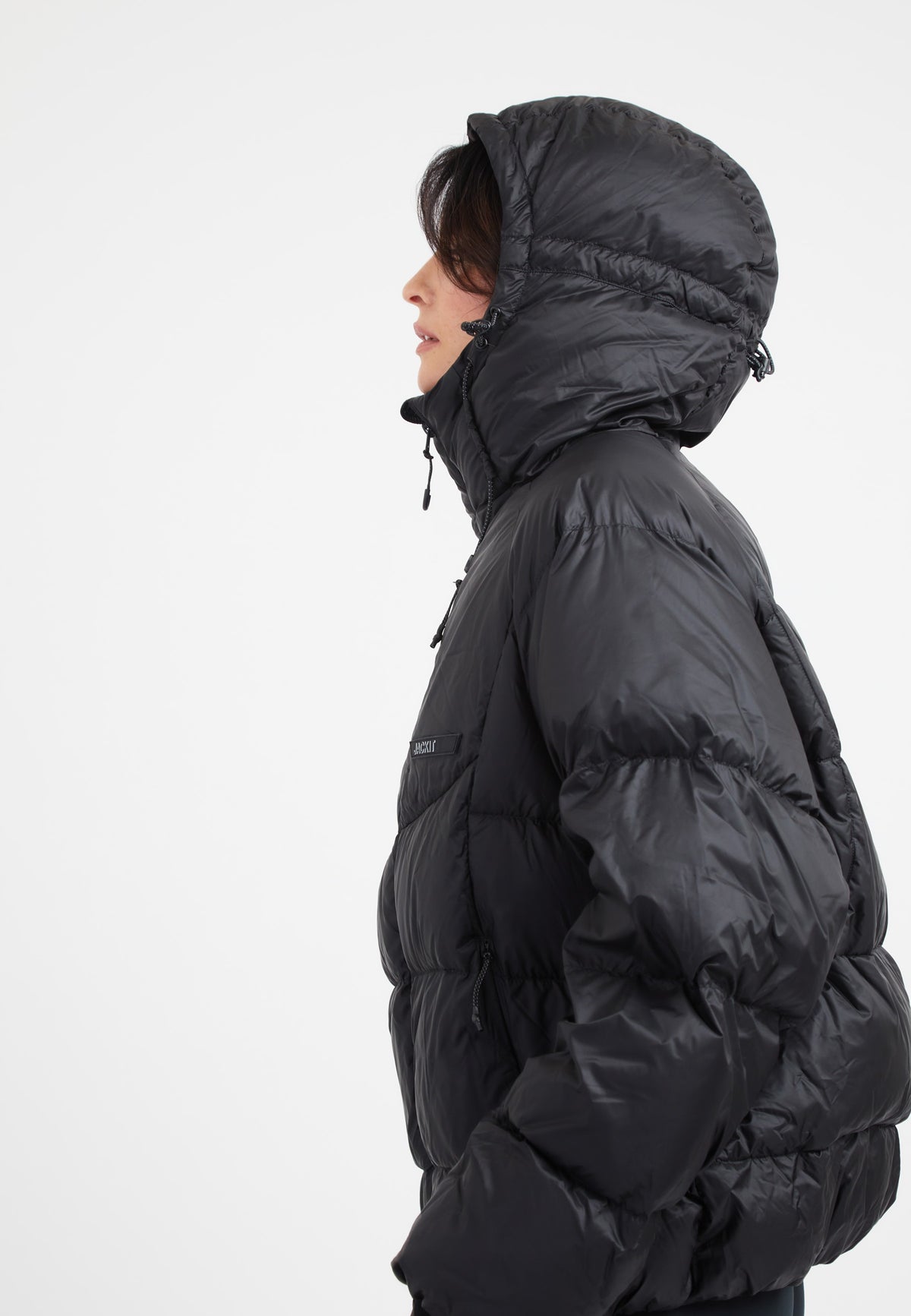 Modern oversized puffer black jacket with adjustable hood and fabric storm cuffs.