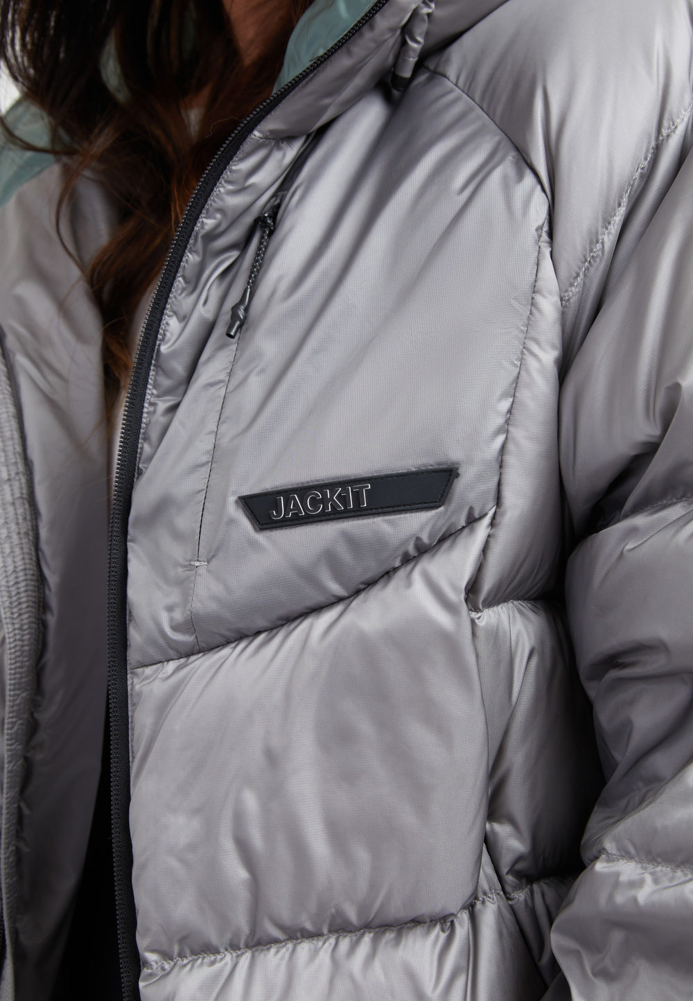 Close-up of a stylish oversized puffer grey jacket featuring a Jackit logo and modern design.