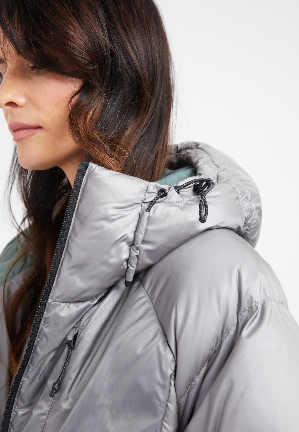 Close-up of a woman wearing an oversized puffer grey jacket with an adjustable hood.