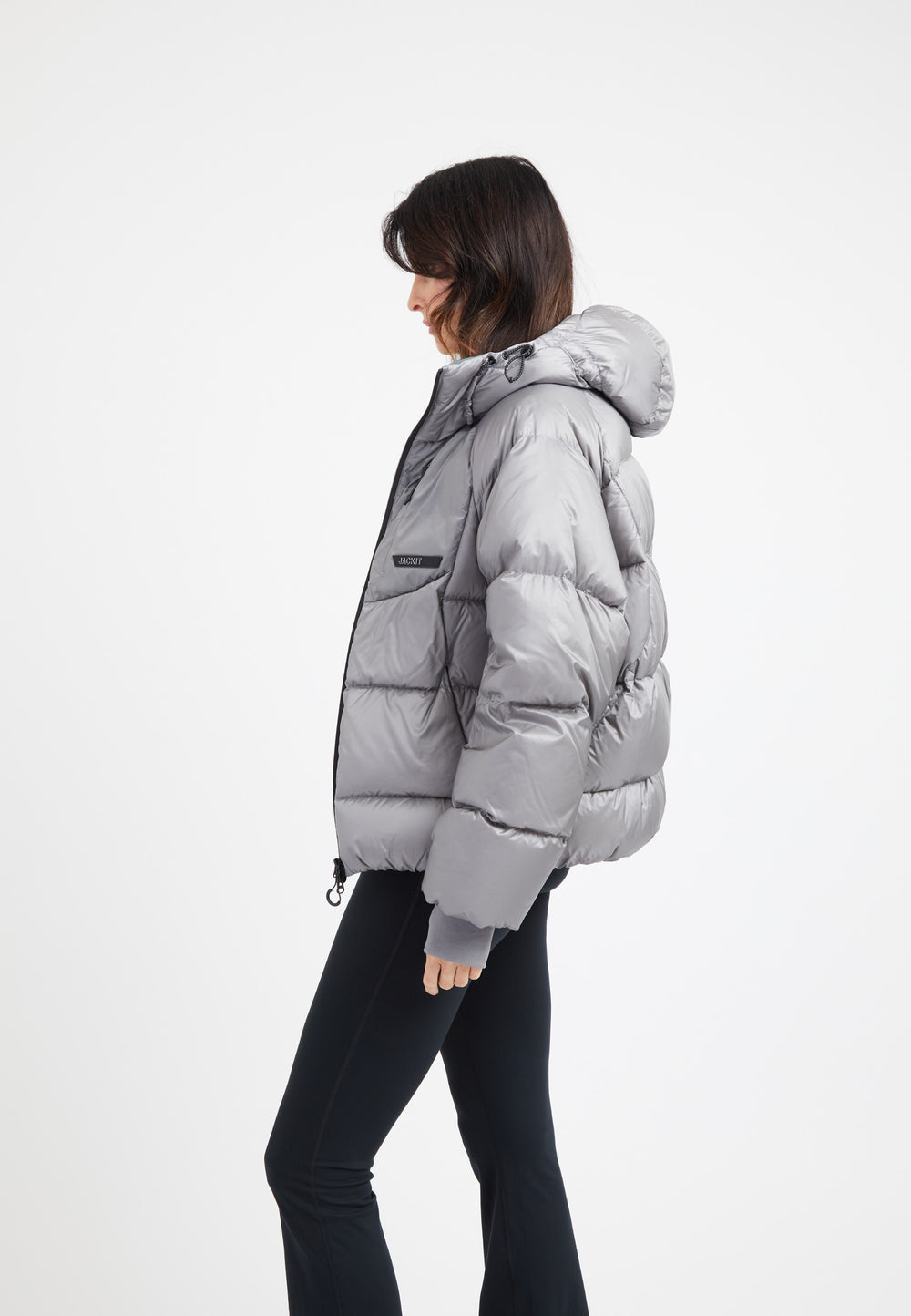 Model wearing an oversized puffer grey jacket with a hood and stylish silhouette.