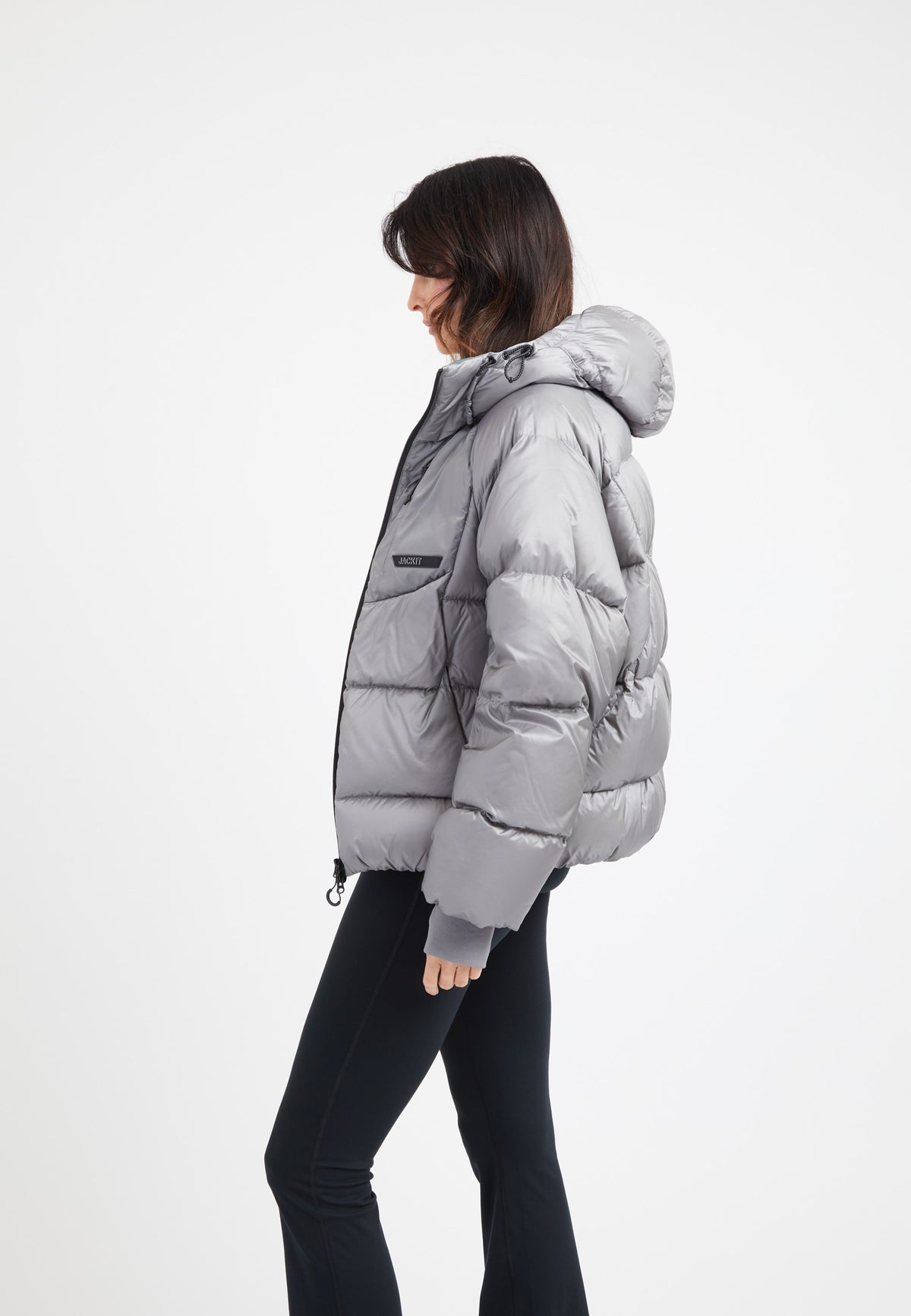 Model wearing an oversized puffer grey jacket with a hood and stylish silhouette.