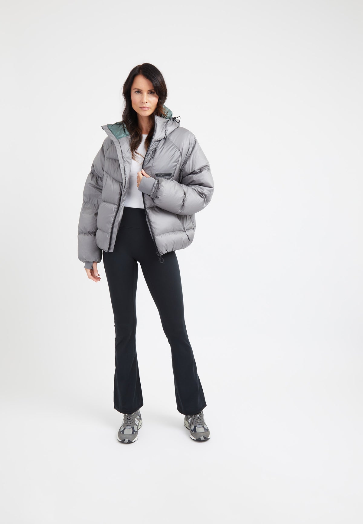 Model wearing oversized puffer grey jacket with black pants and sporty shoes, showcasing a stylish winter look.