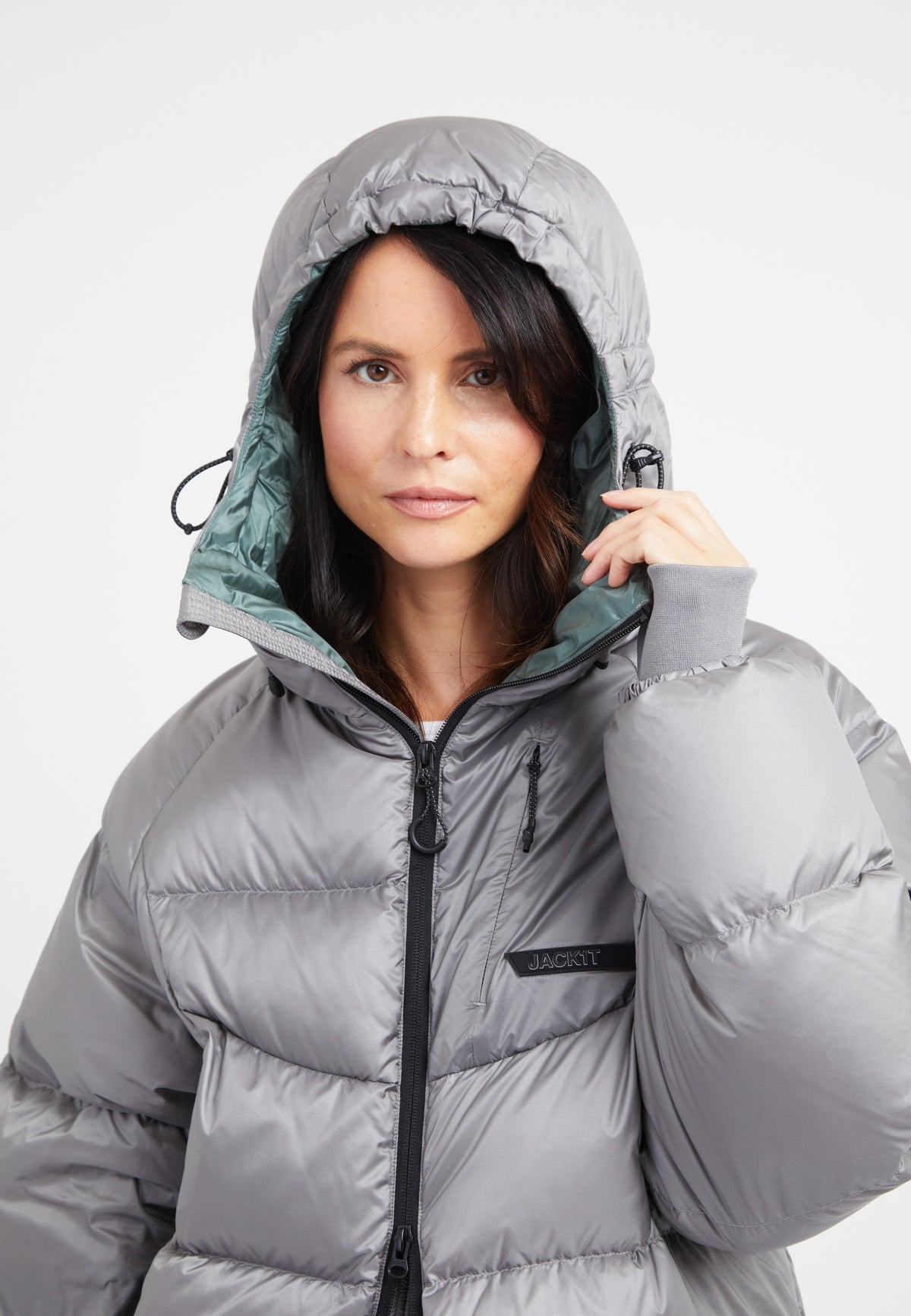 Model wearing an oversized puffer grey jacket with an adjustable hood and fleece-lined hand pockets.