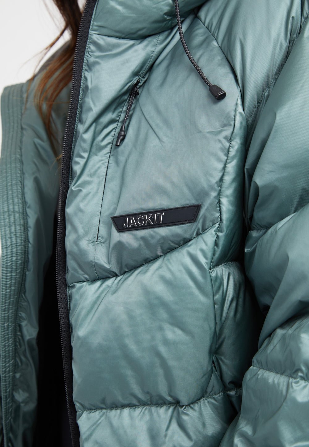 Close-up of an oversized puffer green jacket with a logo tag and a modern design.