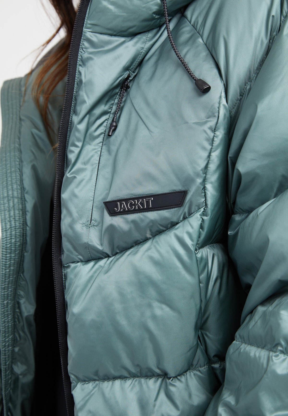 Close-up of an oversized puffer green jacket with a logo tag and a modern design.