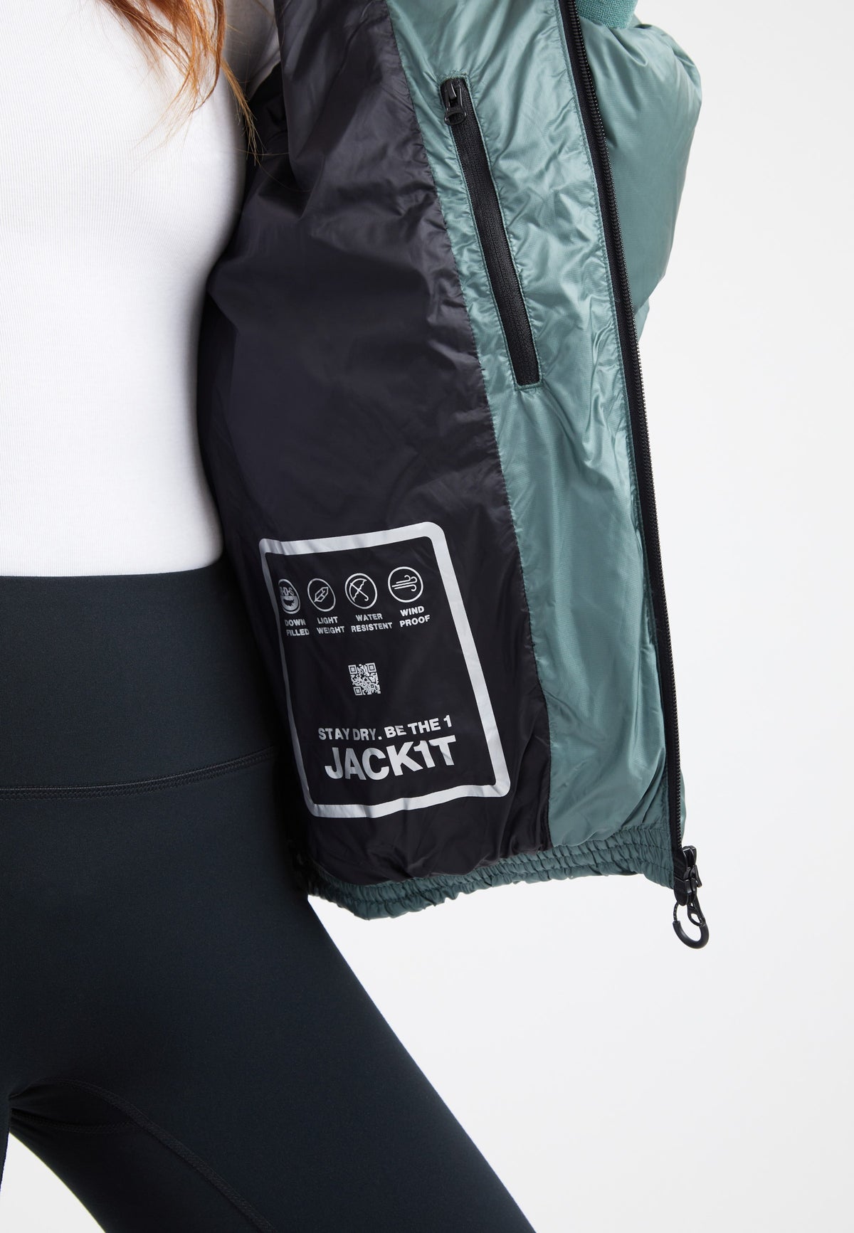 Inside view of an oversized puffer green jacket, showing care label and zipper details on a model.