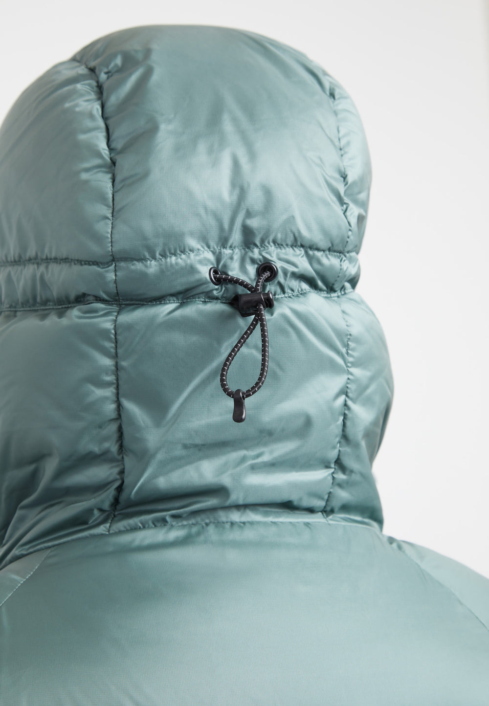 Detail of the adjustable hood on an oversized puffer green jacket, showcasing the fabric and drawstring.
