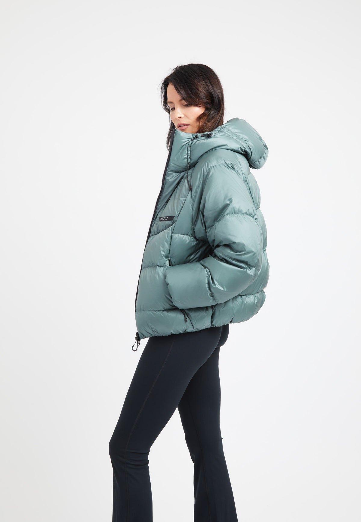 Stylish model wearing an oversized puffer green jacket with a hood and sleek design.
