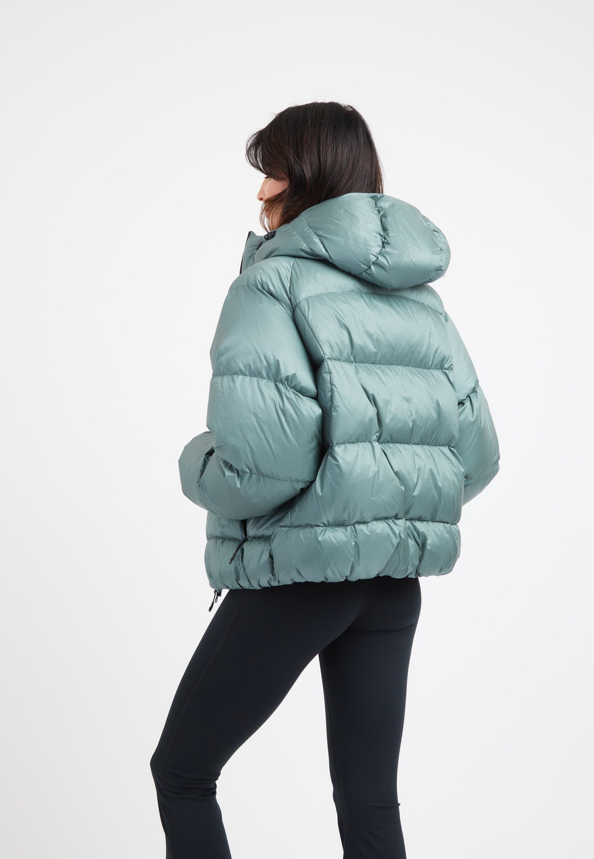 Woman wearing an oversized puffer green jacket, featuring an adjustable hood and modern silhouette.