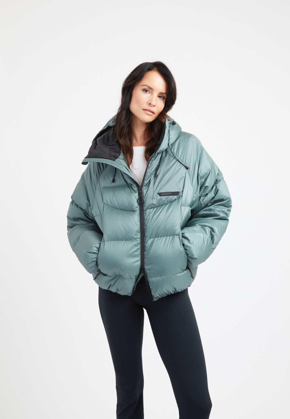 Woman wearing an oversized puffer green jacket with adjustable hood and fleece-lined pockets.