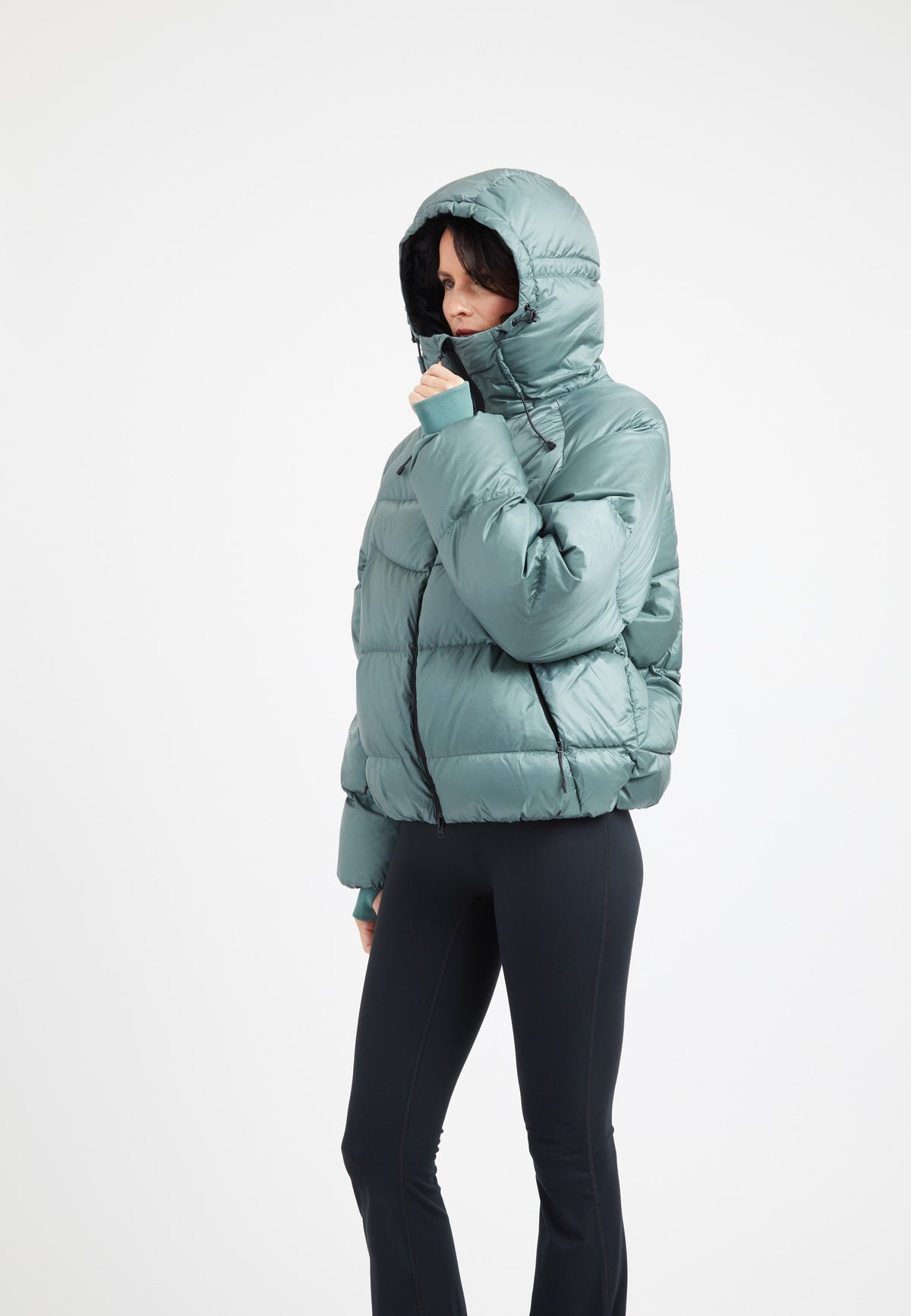 Woman wearing oversized puffer green jacket with adjustable hood and fleece lined pockets.