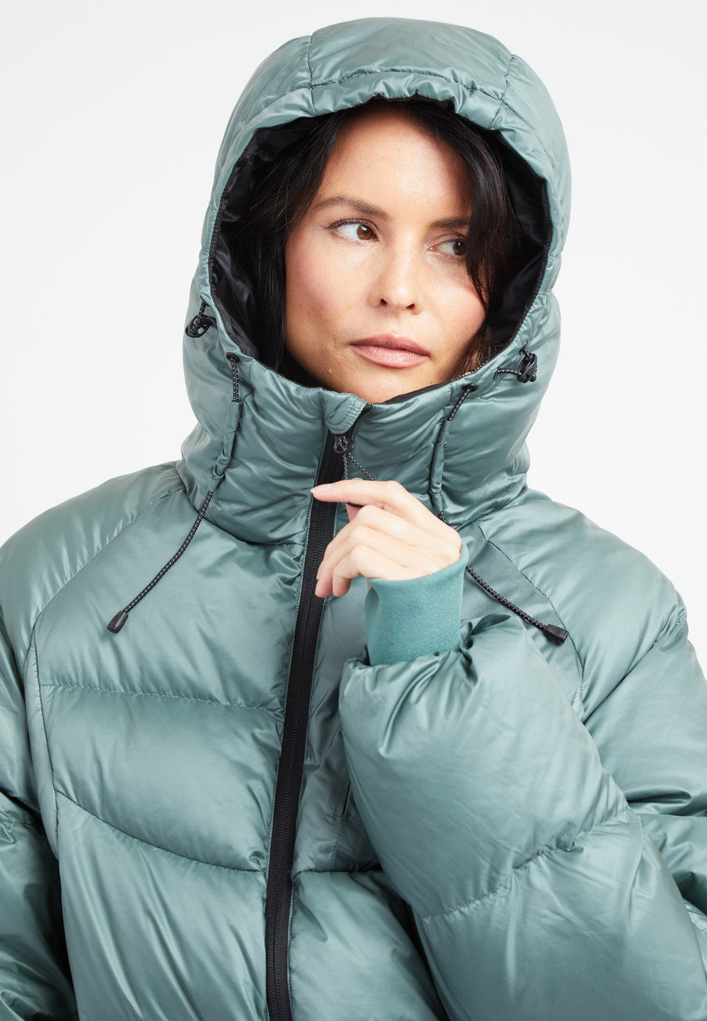 Woman wearing oversized puffer green jacket with adjustable hood, featuring a modern silhouette and cozy design.