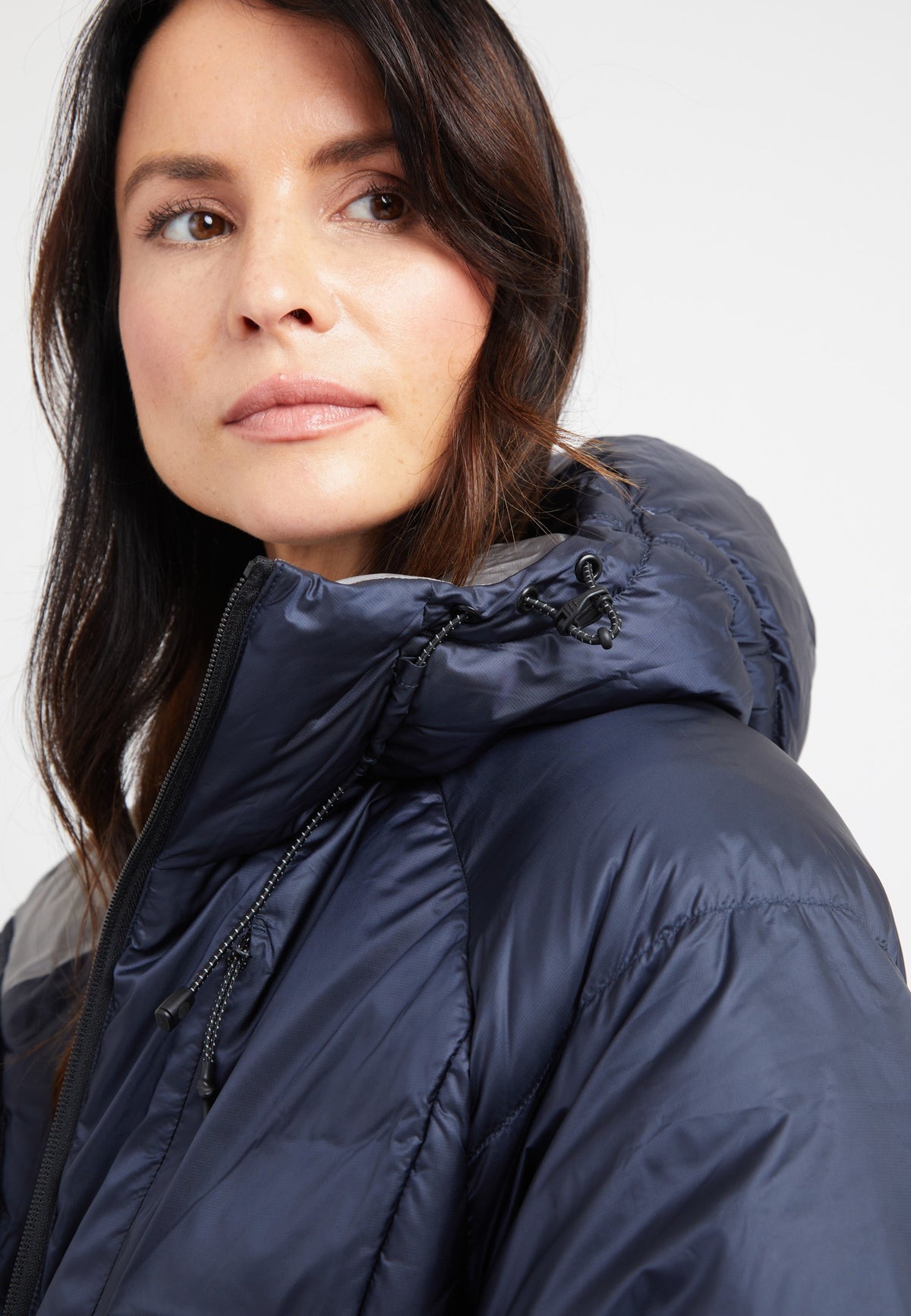 Woman in oversized puffer navy jacket with adjustable hood and stylish modern design.