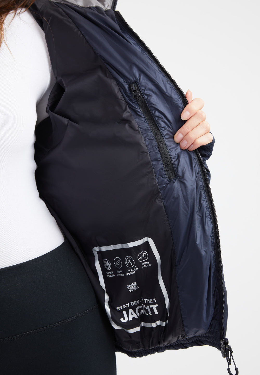 Inside view of oversized puffer navy jacket, showcasing interior pocket and care instructions.